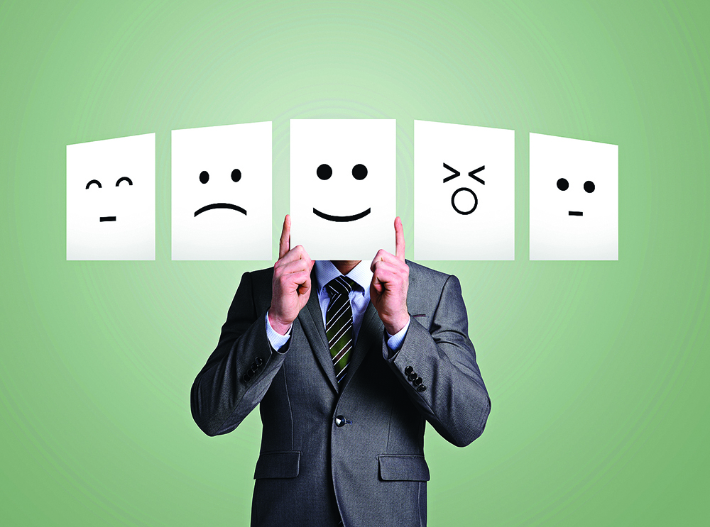 Business man holding up smiley face in front of hi